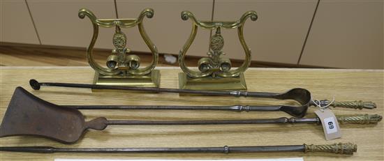 A pair of brass lyre shaped fire dogs and a set of three iron and brass fire implements
